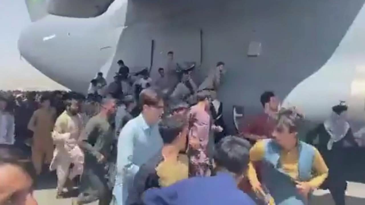 De wanhoop voorbij: Afghanen klimmen op vertrekkend vliegtuig