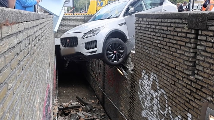 Auto hangt boven voetpad na crash door muur in Rijswijk